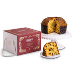 Panettone with a slice removed, displayed on a cake stand next to its packaging box.